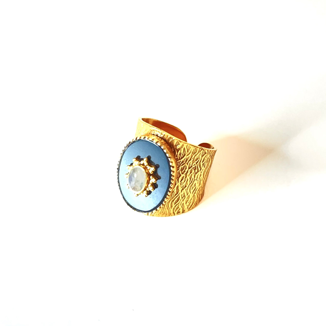 Espectacular anillo de bronce con baño de oro. El detalle central es de Onix con una piedra luna. Este anillo es ajustable lo que lo hace perfecto. Además es super combinable con tu look favorito.