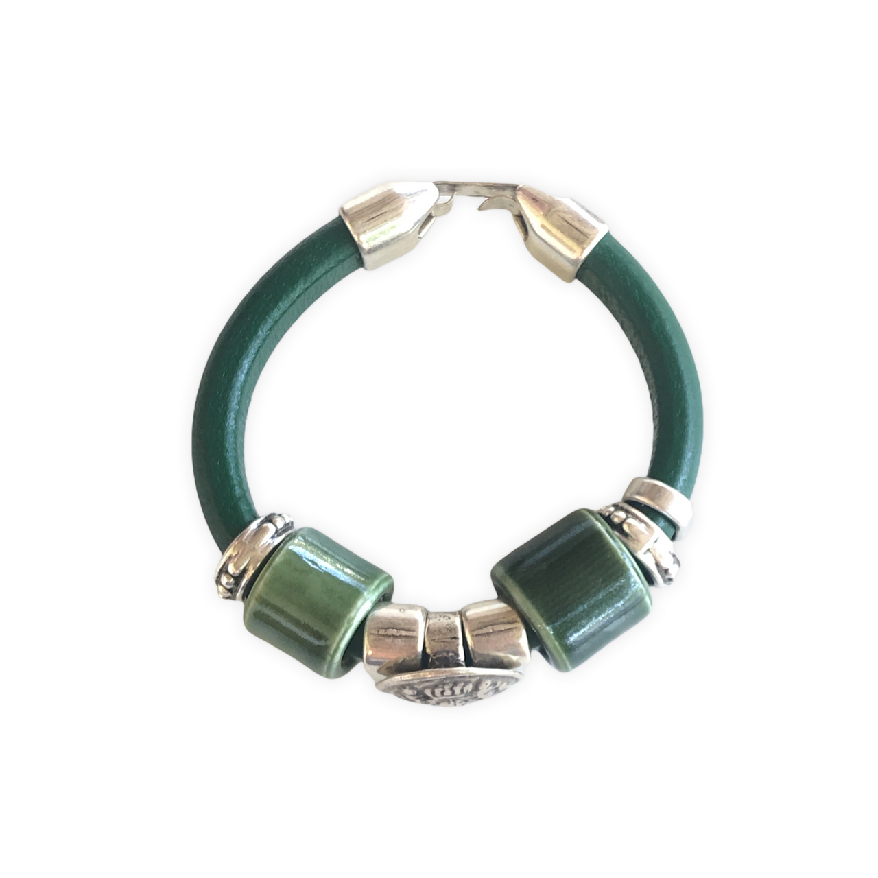 Elegante pulsera de cuero regaliz, con cuentas de Zamak con baño de plata y una espectacular cuenta de cerámica verde. Combínala con tus prendas de diario.